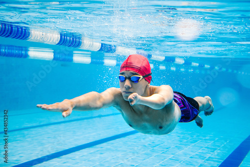 Paralympic Swimmer young latin man Underwater Training In Pool with hand hypoplasia in disability concept