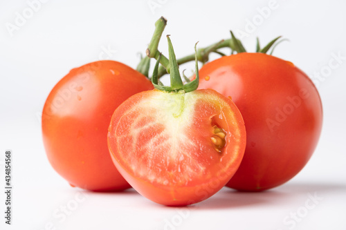 Fresh tomatoes on a green stem on white