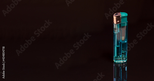 A blue gas lighter on a black reflecting background - copy space