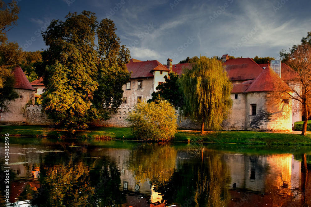 Castle Otočec on the river Krka in southern Slovenia, evening  sunset scene with reflection of castle on the water