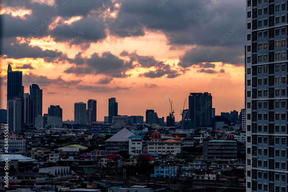 Panorama background of city views, with colorful twilight sky, high-rise buildings (condominiums, offices, expressways) and blurred lights from roads and traffic.