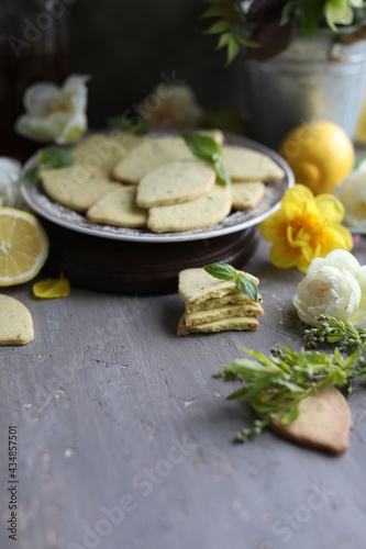 Lemon biscuits with basil on a table with floral decoration. Cookies and spring decor. Crunchy dessert.