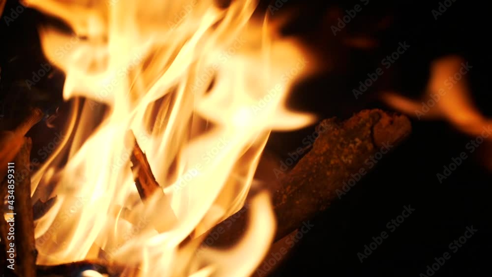 Close-up of tree branches burning in golden flame of burning bonfire on dark background Close-up of tree branches burning in golden flame of burning bonfire on dark background