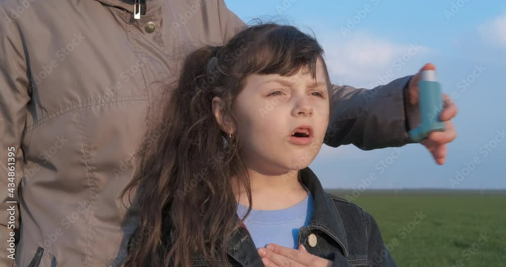 Child with asthma by mother. A stressed daughter has an asthma attack. A woman help her daughter with an inhaler outdoor.