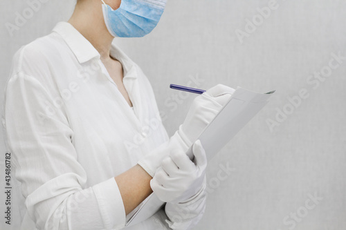 doctor at work.Coronavirus vaccine. Doctor on a detour in a private clinic. doctor in a white coat, gloves, a protective mask and glasses makes notes in a journal.Doctor physician consulting