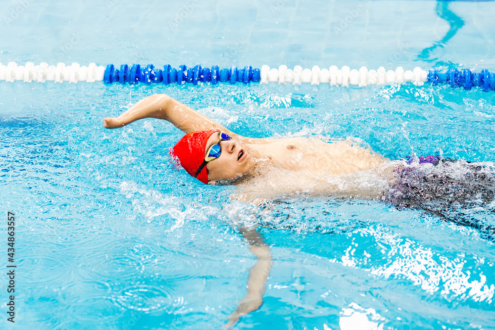 Paralympic Swimmer young hispanic man Training In Pool, Side view of disabled sportsman in goggles and cap in pool between lanes in disability concept in Latin America