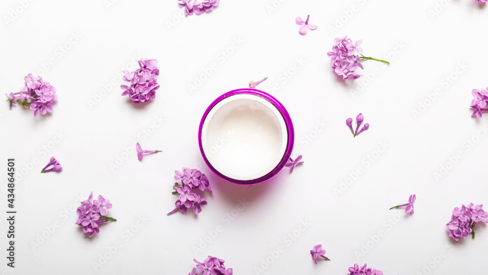 Fototapeta Cosmetic jar containers with purple lilac flowers, blank label packaging for branding mockup, natural organic beauty product concept.