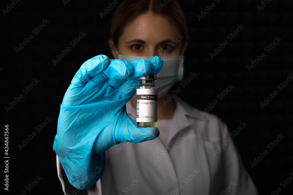 Ampoule with coronavirus vaccine in the doctor's hand on a dark background in the smoke. Ampoule with coronavirus vaccine in the doctor's hand on a dark background in the smoke.