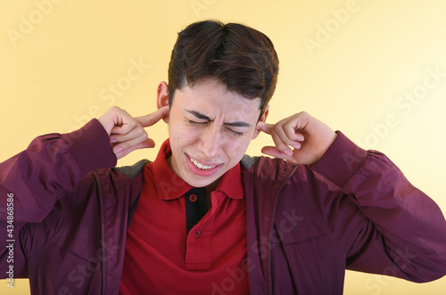 Foto Young man covering his ears due to a loud noise he hears in the street