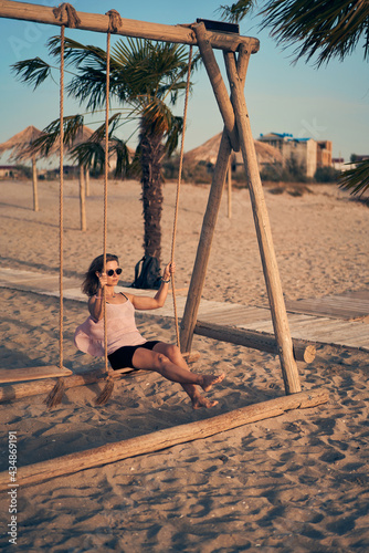 Young attractive woman swinging on seesaw on the beach.