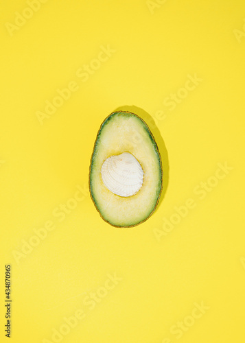 fresh avocado with white seashell in the center on a yellow background.abstract design