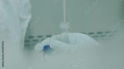 Scientist hand drips liquid in a pipette with measured numbers into volumetric flask