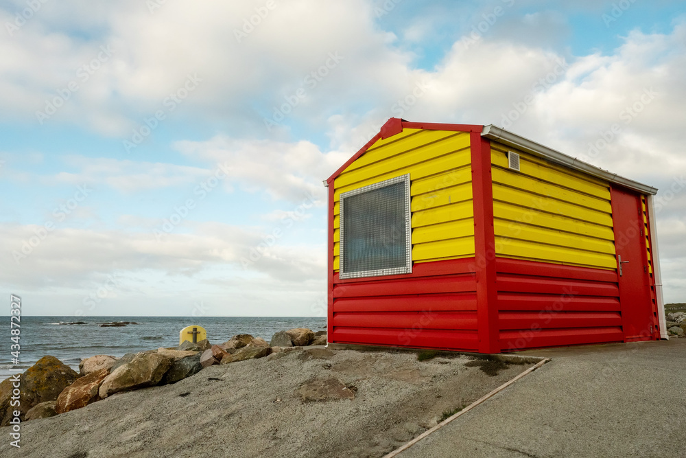 Yellow and bright red lifeguard station by the ocean beach. Public safety measures to save people. Secure place for outdoor activity like swimming and surfing. Cloudy sky. Nobody Yellow and bright red lifeguard station by the ocean beach. Public safety measures to save people. Secure place for outdoor activity like swimming and surfing. Cloudy sky. Nobody