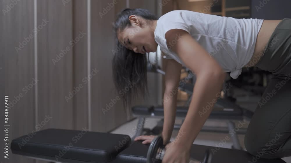 Sportive young women building arm muscle by using a dumbbell in spacious light gym and exercising hardly, no pain no gain, effective activity in daily routine, females weight loss or controlling, 