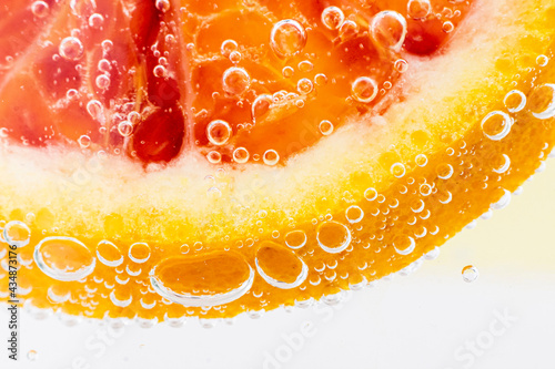 Grapefruit close-up in liquid with bubbles. Slice of blood red ripe grapefruit in water. Part of set.