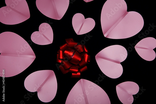 Red gift bow and pink hearts around it.