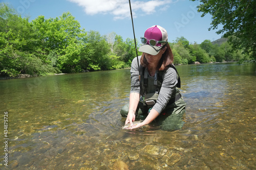 young woman fly fishing and catching a brown trout