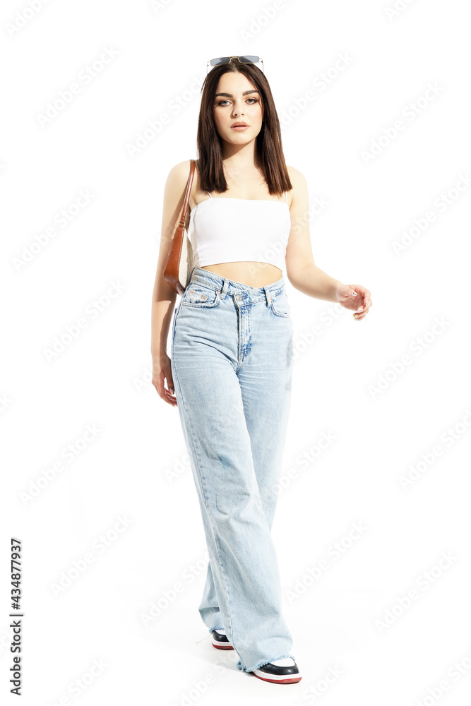Summer girl in sunlight walking and looking at camera with purse and sunglasses on head. Full body length isolated on white background Summer girl in sunlight walking and looking at camera with purse and sunglasses on head. Full body length isolated on white background