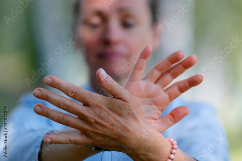 Woman practicing Qi Gong or Tai Chi exercise   in nature. Close up on hands. photo