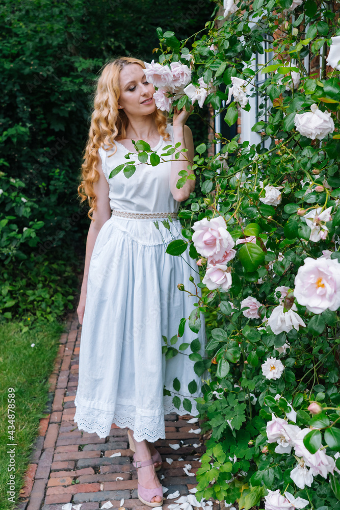 Woman smelling and enjoying beautiful roses flowers beautiful sunny spring day. Smiling young woman posing with blossom flowers having positive emotion. female face with flowers. Woman smelling and enjoying beautiful roses flowers beautiful sunny spring day. Smiling young woman posing with blossom flowers having positive emotion. female face with flowers.