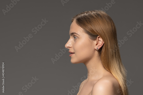 Portrait of young female fashion model isolated on grey studio background. Beautiful caucasian woman with well-kept skin.