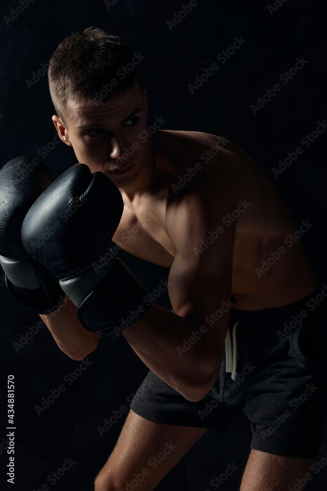 boxer in gloves on a black background bent down 