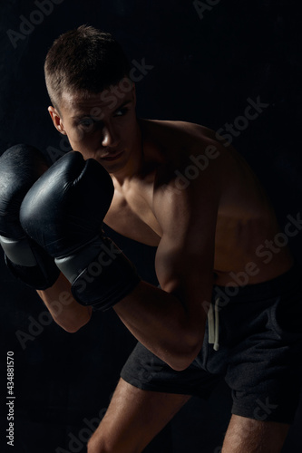 boxer in gloves on a black background bent down 