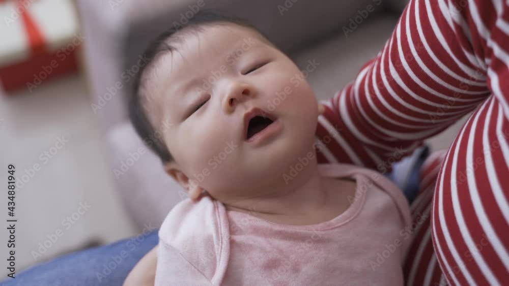 headshot of asian lovely baby is breathing with mouth while she is sound asleep in a woman caretaker’s arms in the morning at home. headshot of asian lovely baby is breathing with mouth while she is sound asleep in a woman caretaker’s arms in the morning at home.