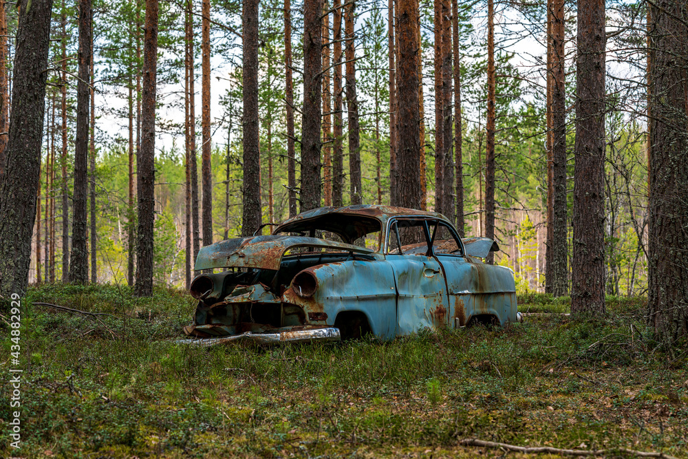 Old blue car wreck standing in a forest in Sweden Old blue car wreck standing in a forest in Sweden