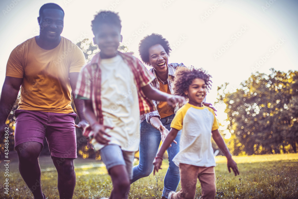 Fototapeta premium African American family having fun outdoors. Focus is on woman face. Happy family enjoying in the nature.