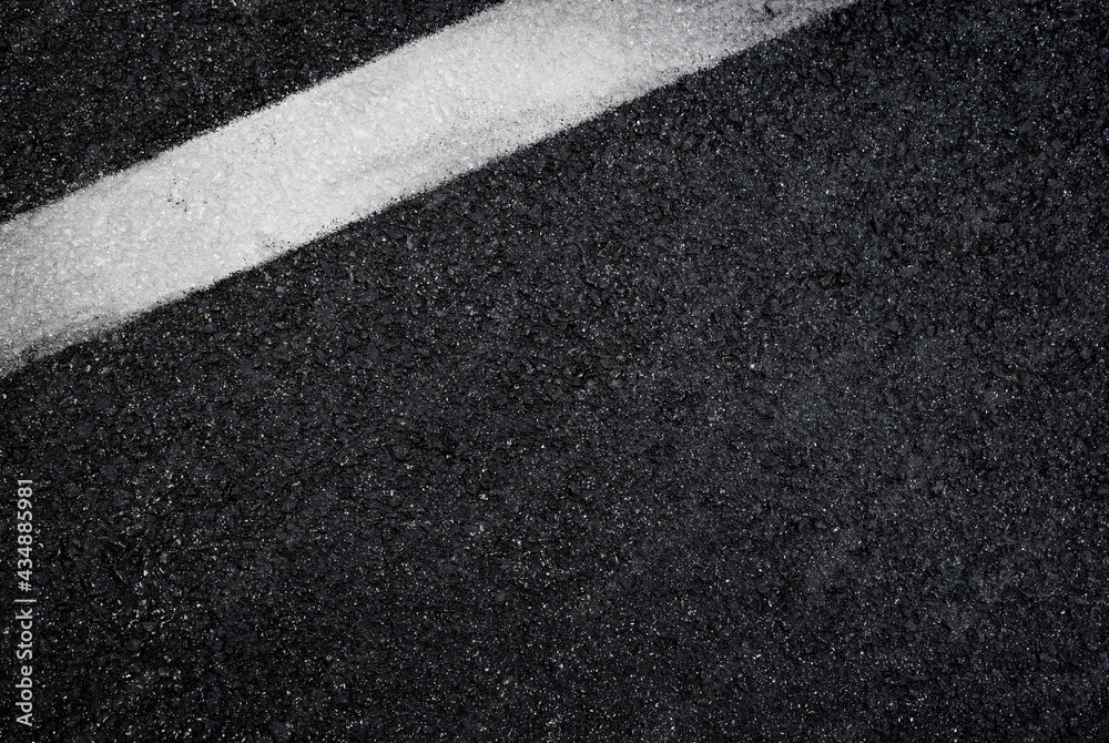 Fototapeta premium Top view of dark wet asphalt road with white line. High resolution full frame textured background of black asphalt, viewed from above. Copy space.