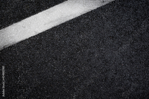 Top view of dark wet asphalt road with white line. High resolution full frame textured background of black asphalt, viewed from above. Copy space. © tuomaslehtinen