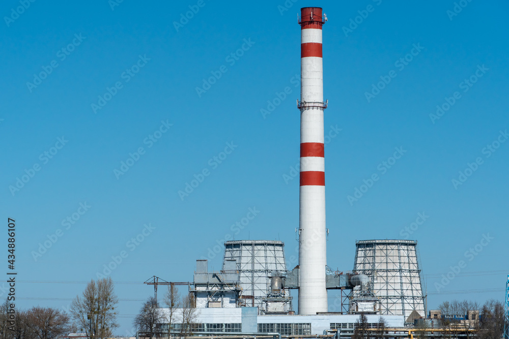 View of a thermal power plant or a factory for the production and processing of petroleum products. Large industrial chimneys against a clear blue sky. Removal of combustion
