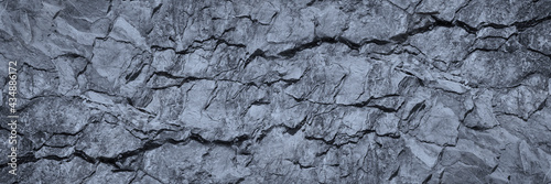 Gray rock texture with cracks. Stone wall background with copy space for text and design. Wide banner. Rocky surface. Close-up.