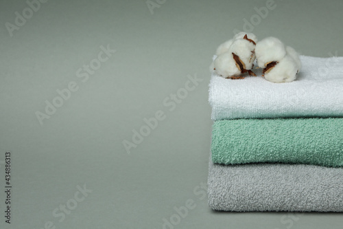 Clean folded towels with cotton on gray background