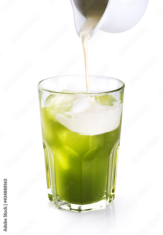 Milk pouring into glass with matcha iced tea isolated on white background. Milk pouring into glass with matcha iced tea isolated on white background.