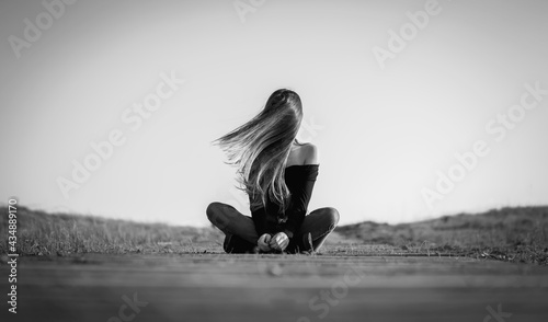 Chica de pelo largo sentada en el camino golpeada por el viento disfrutando del invierno © xin