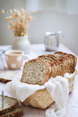 A loaf of multi grains and cereals healthy flourless bread with low calories and vegan in a bamboo basket, cup of coffee in background. High in proteins. Paleo and ketogenic diet 
