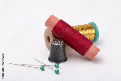 Bilde på lerret Spools with red and yellow threads, metal thimble and pins with green heads on a