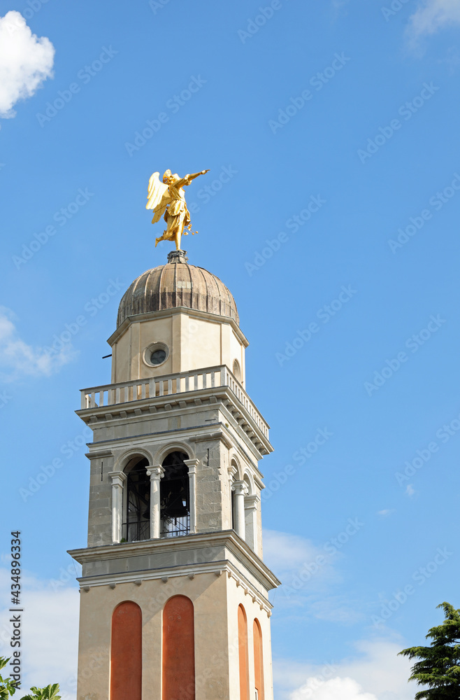 golden statue of a large angel above the bell tower of the castle in the city of Udine in northern Italy