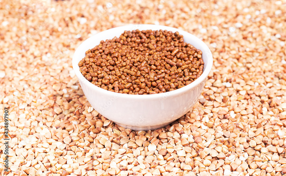Granules of caffein-free buckwheat tea in a white plate on a background of raw buckwheat Granules of caffein-free buckwheat tea in a white plate on a background of raw buckwheat