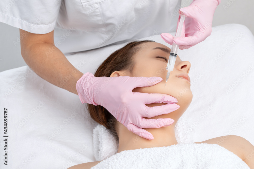Cosmetologist makes lipolytic injections to burn fat on the chin, cheeks and neck of a woman against double chin. Female aesthetic cosmetology in a beauty salon.Cosmetology concept. Cosmetologist makes lipolytic injections to burn fat on the chin, cheeks and neck of a woman against double chin. Female aesthetic cosmetology in a beauty salon.Cosmetology concept.