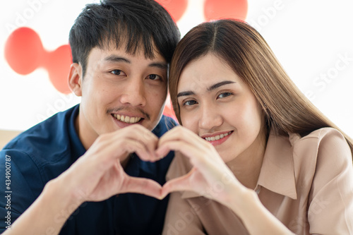 Asian man and woman gesturing heart