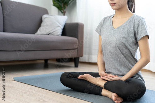 A beautiful woman practicing yoga and meditation in the living room at home. Calm and set breath for good physical and mental health.