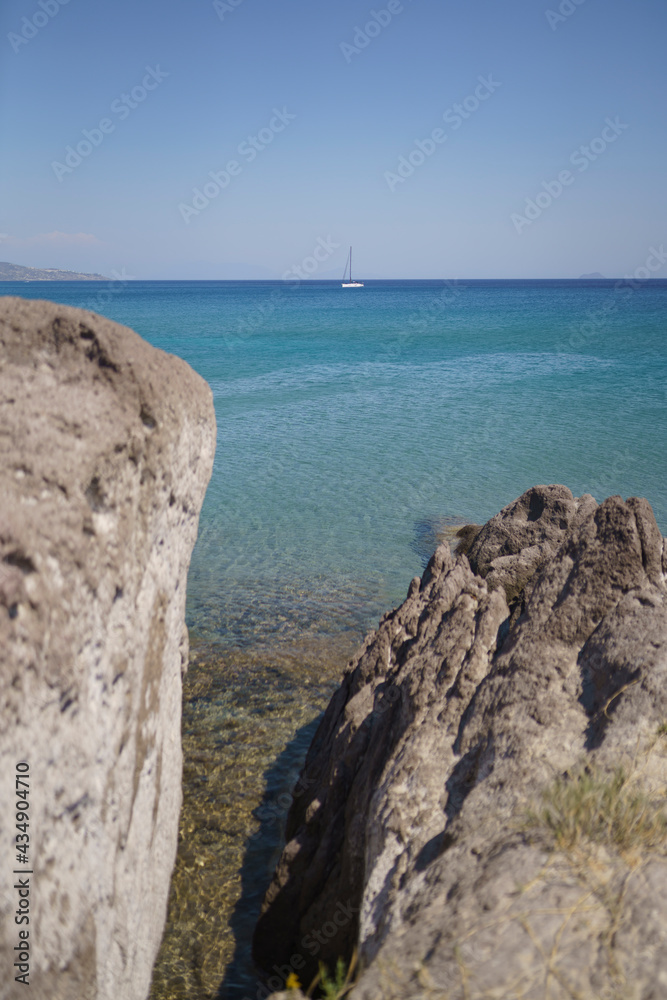 Felswand mit Meer und Boot im Hintergrund
