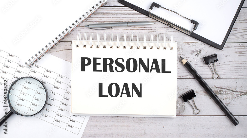 Notepad with text PERSONAL LOAN with a pen,office tools and graphs on the desktop. Notepad with text PERSONAL LOAN with a pen,office tools and graphs on the desktop.