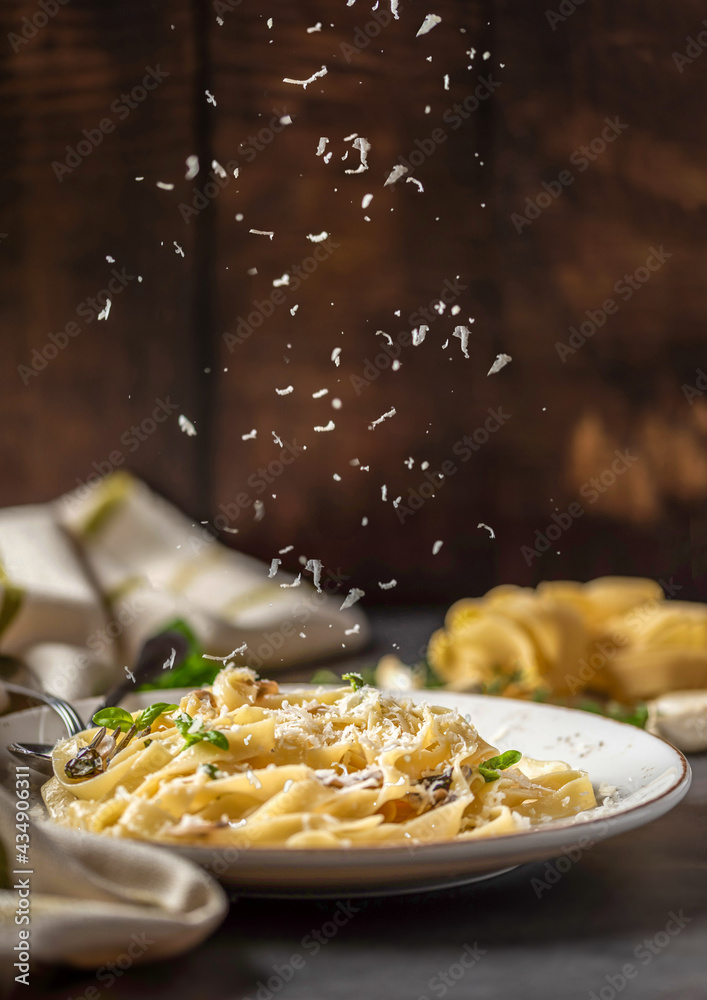 Pasta fettuccine with mushrooms and fried chicken ham in creamy cheese sauce on a light wooden background - obrazy, fototapety, plakaty 