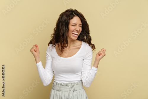 фотографія Happy young woman gesturing in triumph with toothy smile, closed eyes, hold fists up celebrate success, lottery win