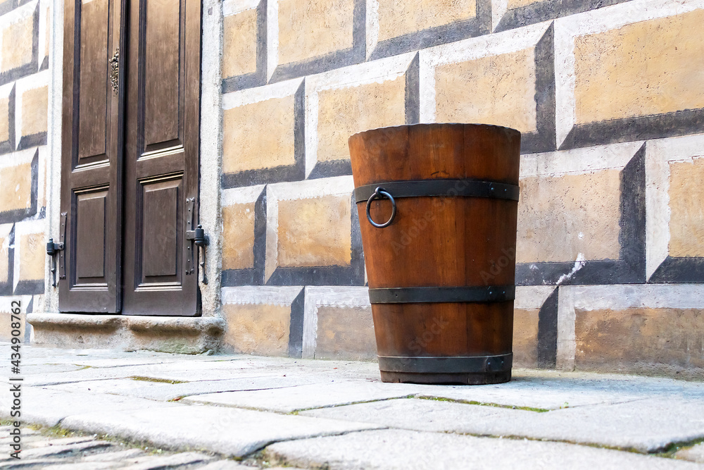 an old brown wooden barrel and door in the historic courtyard with stone paving, castle Cesky Krumlov, Czech republic an old brown wooden barrel and door in the historic courtyard with stone paving, castle Cesky Krumlov, Czech republic