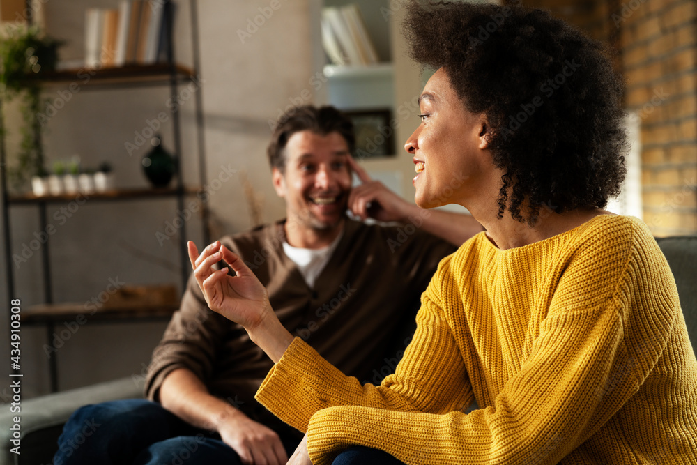 Young couple sitting and talking at home. Woman and man flirting and laughing.. Young couple sitting and talking at home. Woman and man flirting and laughing..